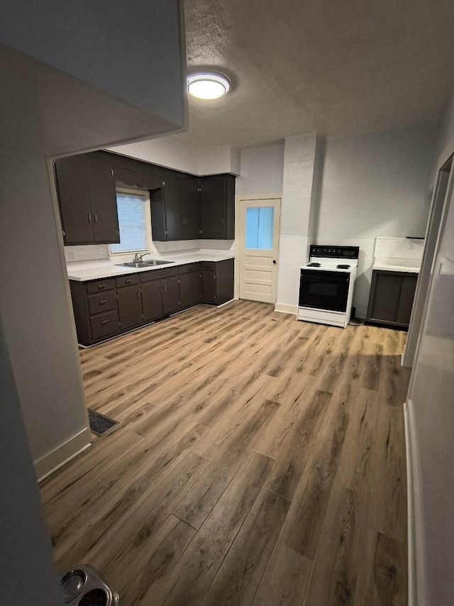 kitchen featuring visible vents, light countertops, light wood-style flooring, range with electric stovetop, and a sink