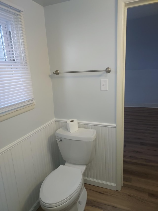 bathroom featuring toilet, wood finished floors, and wainscoting