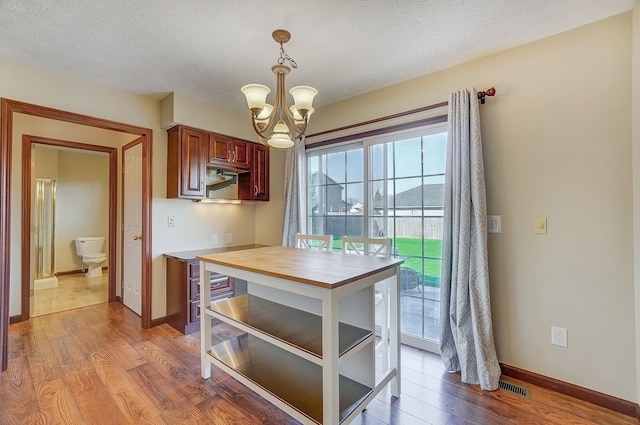 kitchen featuring a chandelier, wood finished floors, baseboards, and hanging light fixtures