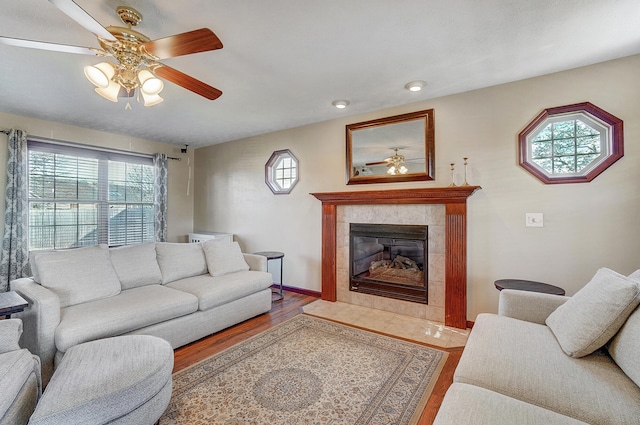 living room with wood finished floors, ceiling fan, baseboards, and a tile fireplace