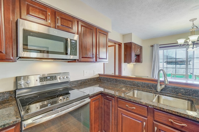 kitchen with a textured ceiling, a chandelier, a sink, stainless steel appliances, and decorative light fixtures