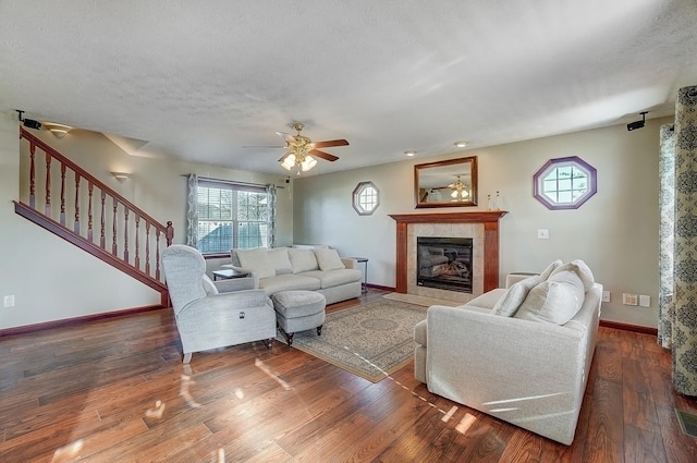 living area with baseboards, wood finished floors, a tiled fireplace, and plenty of natural light
