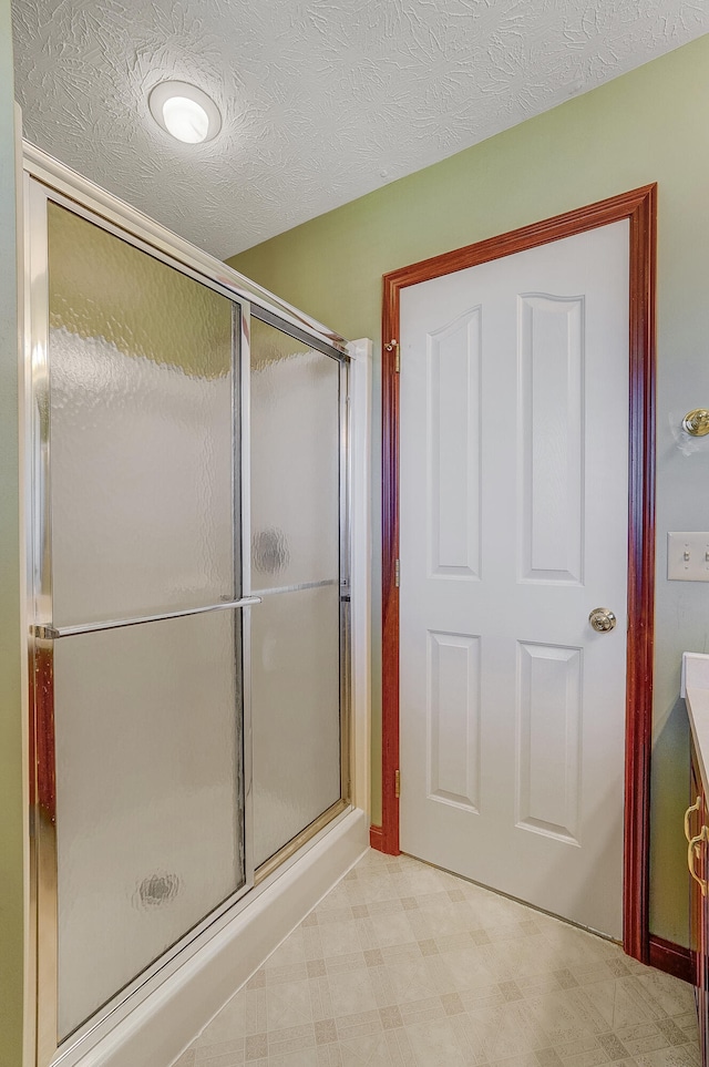 bathroom featuring tile patterned floors, a shower with door, and a textured ceiling