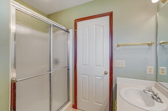 full bathroom with a shower stall, a textured ceiling, and a sink