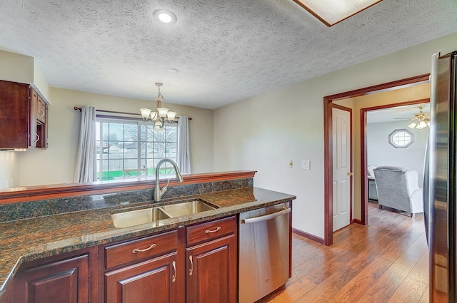 kitchen featuring a notable chandelier, decorative light fixtures, a sink, light wood finished floors, and stainless steel appliances