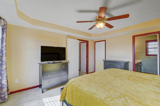 bedroom with baseboards, a raised ceiling, ensuite bath, ceiling fan, and carpet