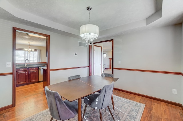 dining room featuring a notable chandelier, light wood-type flooring, and visible vents
