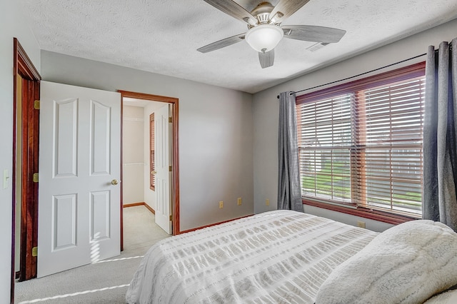 carpeted bedroom with visible vents, ceiling fan, baseboards, and a textured ceiling