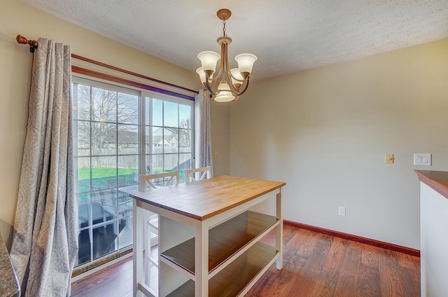 unfurnished dining area featuring a chandelier, baseboards, hardwood / wood-style flooring, and a textured ceiling