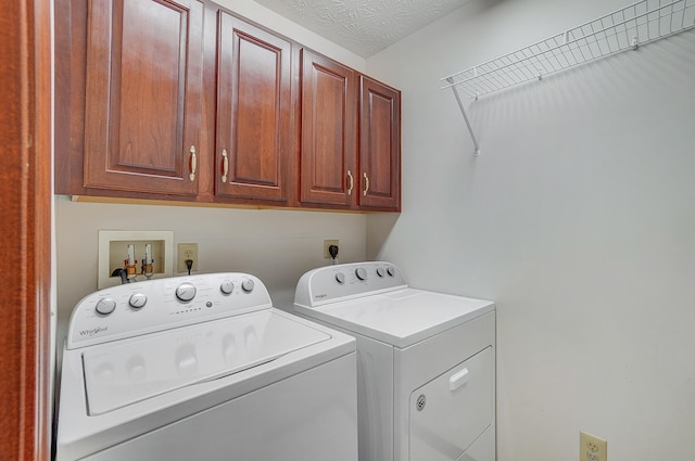 laundry room with washer and clothes dryer, a textured ceiling, and cabinet space