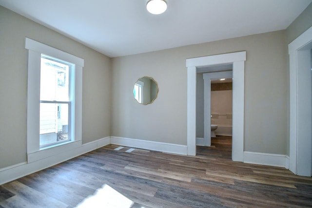 spare room featuring a wealth of natural light and dark hardwood / wood-style floors