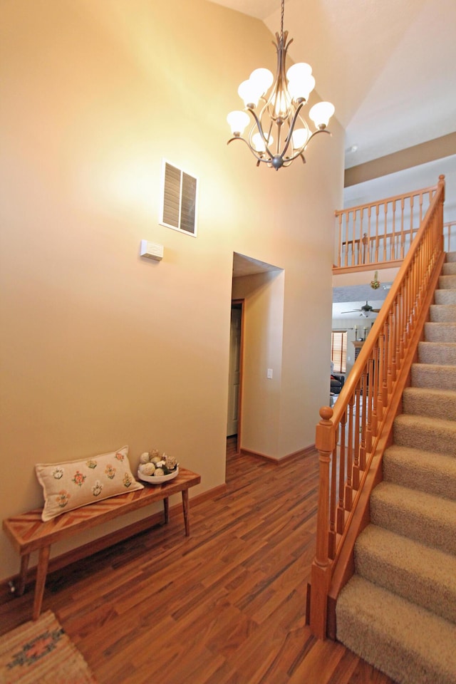 interior space with visible vents, baseboards, wood finished floors, high vaulted ceiling, and a notable chandelier