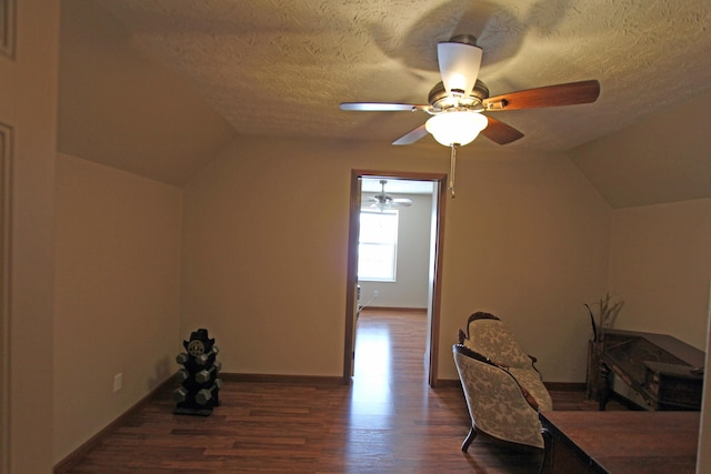 bonus room featuring baseboards, dark wood finished floors, ceiling fan, vaulted ceiling, and a textured ceiling