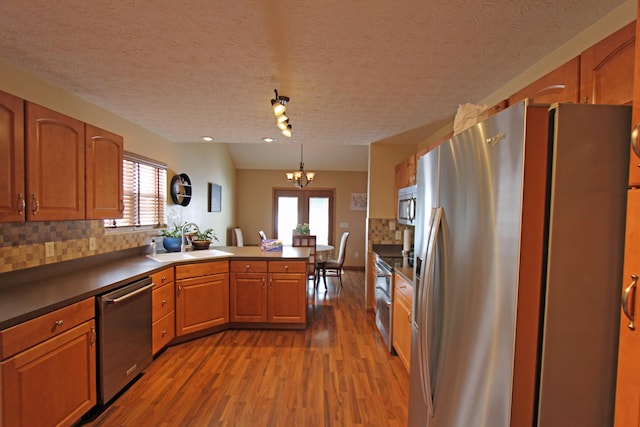 kitchen featuring dark countertops, brown cabinetry, stainless steel appliances, and a sink