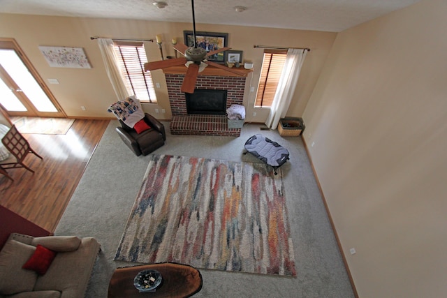 609 Lambert Dr, Piqua, OH 45356 - carpeted living room featuring wood finished floors, a brick fireplace, a textured ceiling, baseboards, and ceiling fan