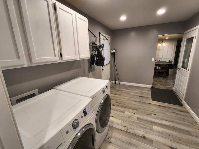 laundry area featuring cabinets, washer and clothes dryer, an inviting chandelier, and light wood-type flooring