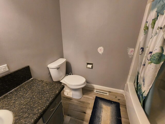 full bathroom with wood-type flooring, shower / bath combo with shower curtain, toilet, and vanity