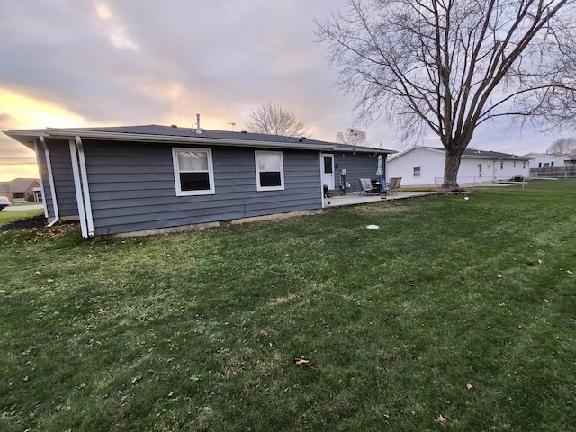 back house at dusk with a yard and a patio