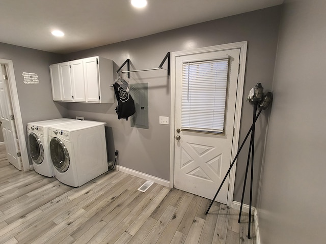 washroom featuring cabinets, electric panel, light hardwood / wood-style flooring, and washing machine and clothes dryer