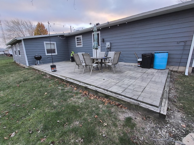 back house at dusk with a patio and a yard