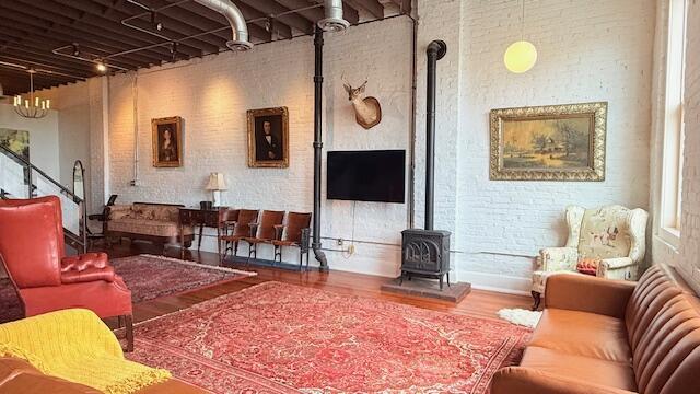 living area featuring a wood stove, wood finished floors, brick wall, and track lighting