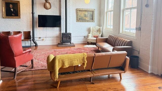 living area with a wood stove, wood finished floors, and baseboards