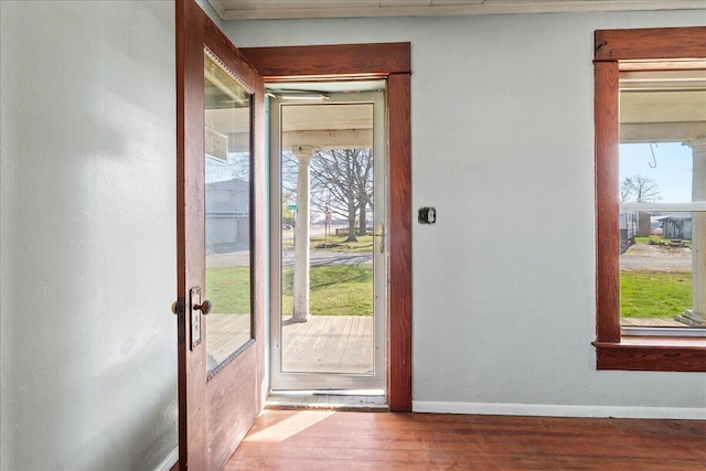 doorway to outside featuring plenty of natural light, baseboards, and wood finished floors