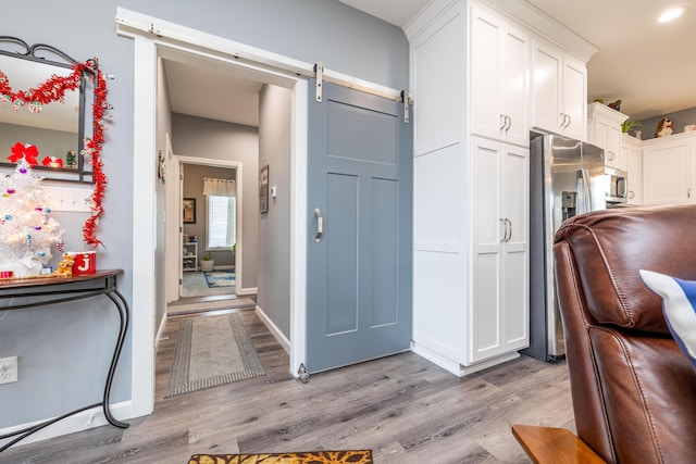 255 N Pine St, Lakeview, OH 43331 - kitchen featuring a barn door, light wood-style flooring, appliances with stainless steel finishes, and white cabinets