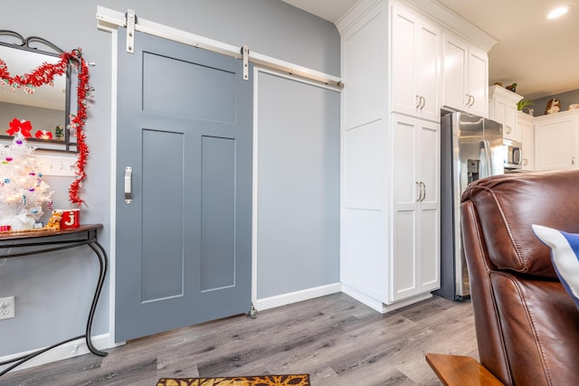 255 N Pine St, Lakeview, OH 43331 - kitchen with a barn door, light wood-style flooring, white cabinetry, and stainless steel appliances
