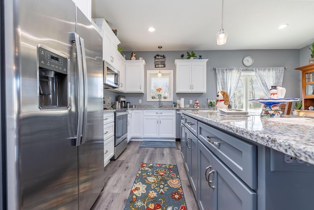 255 N Pine St, Lakeview, OH 43331 - kitchen featuring stainless steel appliances, white cabinetry, decorative light fixtures, wood finished floors, and light stone counters