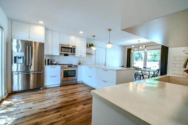 1138 Edgebrook Ave, New Carlisle, OH 45344 - kitchen with appliances with stainless steel finishes, a peninsula, dark wood-style floors, backsplash, and pendant lighting