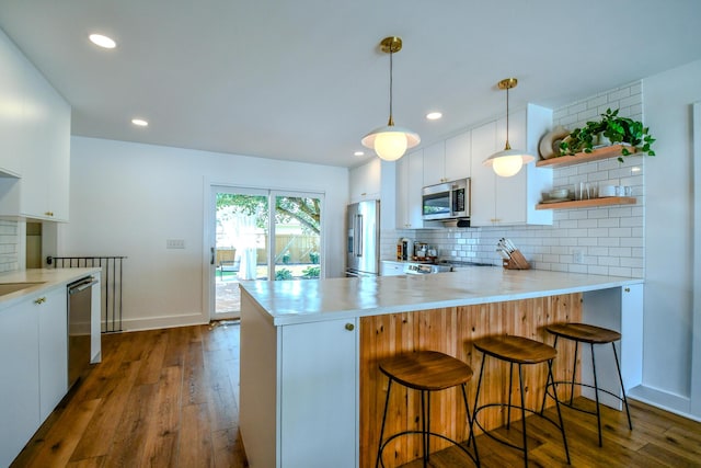 1138 Edgebrook Ave, New Carlisle, OH 45344 - kitchen with appliances with stainless steel finishes, dark wood-style flooring, backsplash, a peninsula, and white cabinets
