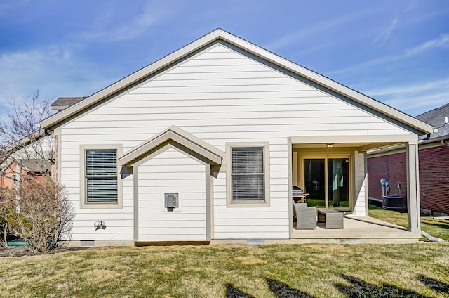 rear view of property with crawl space, a patio area, and a lawn