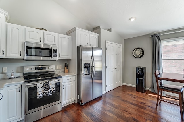 kitchen with lofted ceiling, stainless steel appliances, dark wood-type flooring, and light countertops