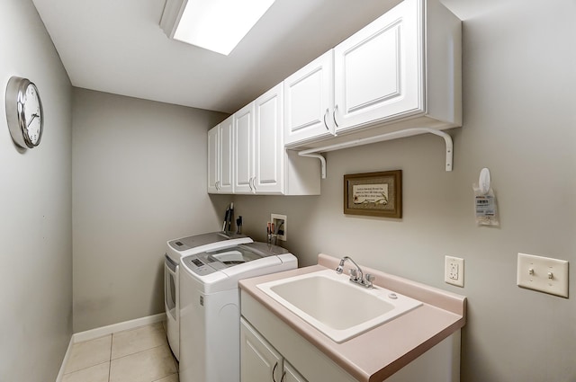 clothes washing area with cabinet space, light tile patterned floors, baseboards, independent washer and dryer, and a sink