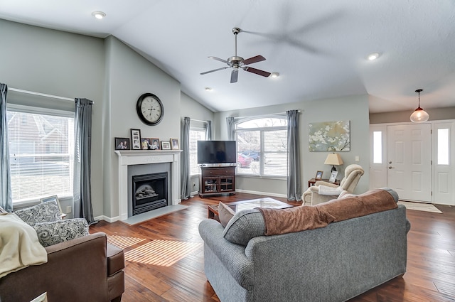 living room featuring vaulted ceiling, dark wood-type flooring, a fireplace with flush hearth, and baseboards