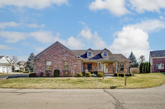 view of front of home with covered porch, a front lawn, and brick siding