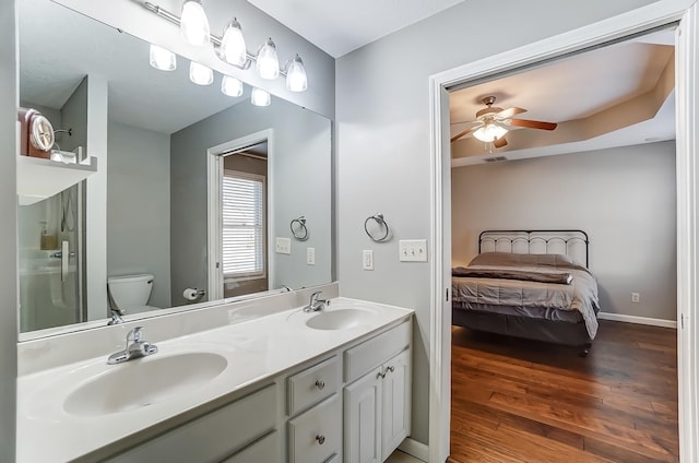 bathroom with double vanity, a sink, toilet, and wood finished floors