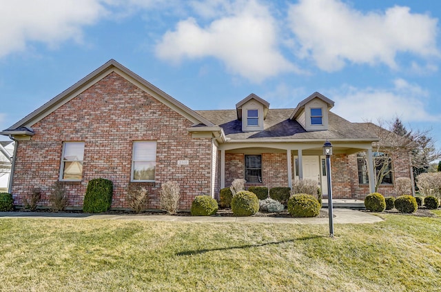 view of front of home featuring a porch, a front yard, and brick siding