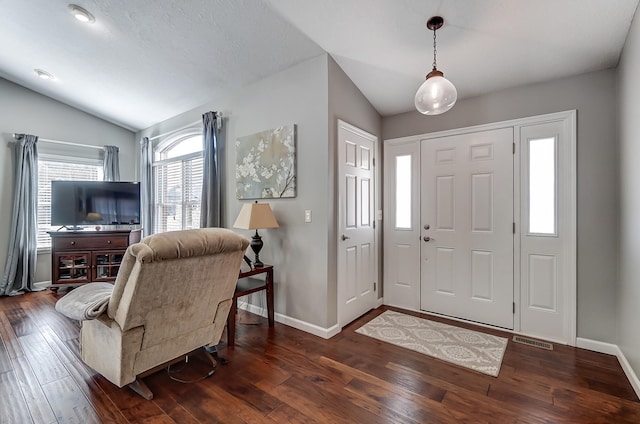 foyer featuring lofted ceiling, wood-type flooring, visible vents, and baseboards