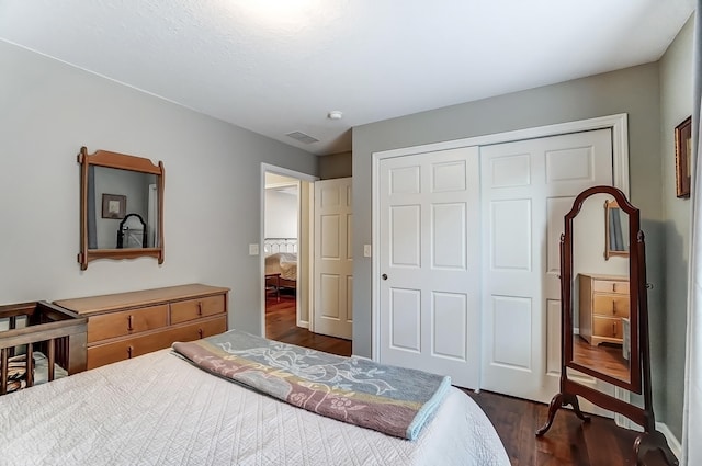 bedroom featuring visible vents, dark wood finished floors, and a closet