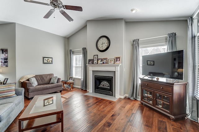 living area featuring dark wood finished floors, a fireplace with flush hearth, vaulted ceiling, ceiling fan, and baseboards