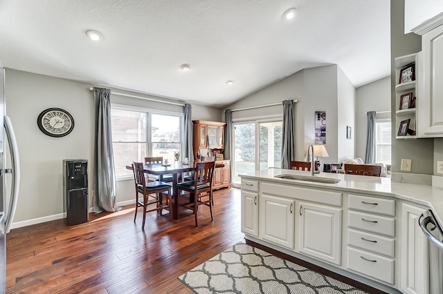 kitchen featuring lofted ceiling, dark wood-type flooring, a peninsula, light countertops, and a sink