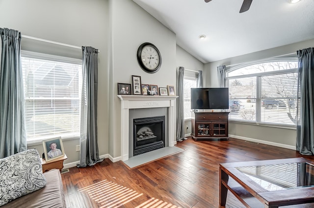 living area with a fireplace with flush hearth, wood finished floors, a ceiling fan, vaulted ceiling, and baseboards