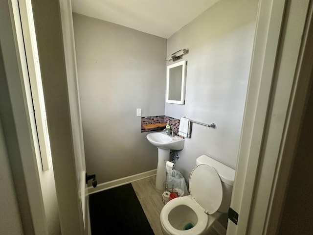 half bath with wood finished floors, toilet, and baseboards