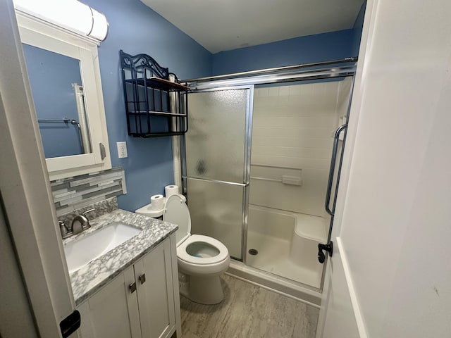 full bathroom with toilet, wood finished floors, vanity, and a stall shower