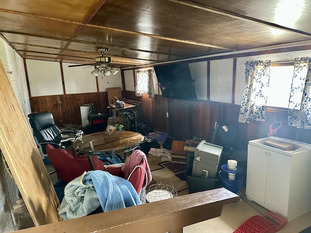 interior space with wainscoting, wooden walls, a sink, and ceiling fan