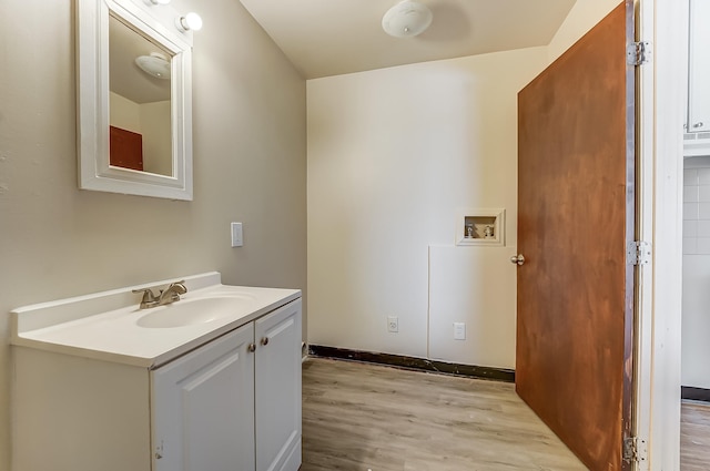 bathroom featuring baseboards, wood finished floors, and vanity