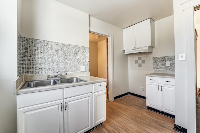 kitchen featuring light wood-type flooring, a sink, white cabinets, and under cabinet range hood