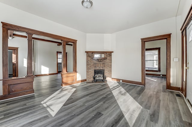 unfurnished living room featuring visible vents, ornate columns, and wood finished floors